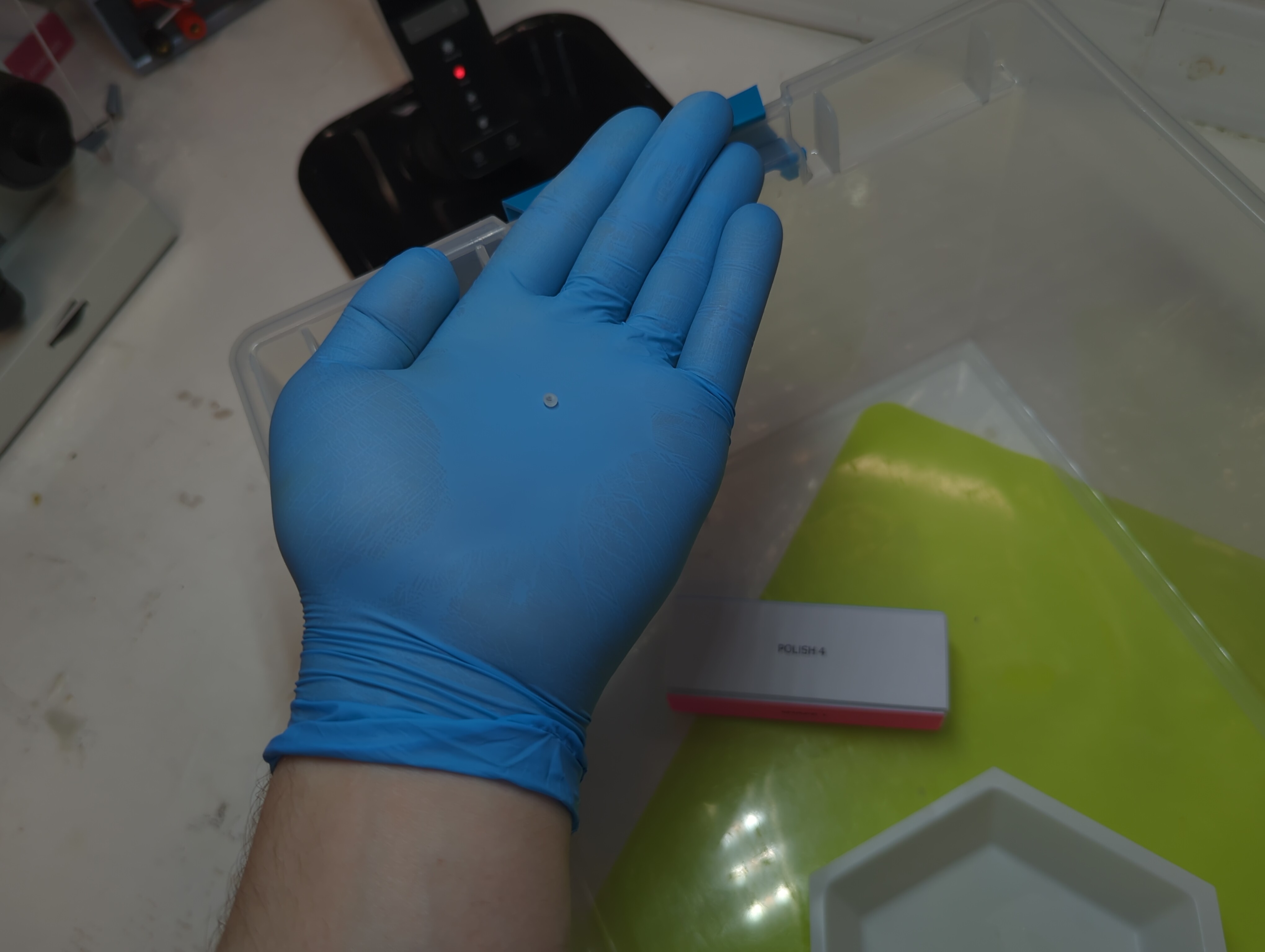 A bead of encapsulated flesh in a gloved hand, with a sanding block in view