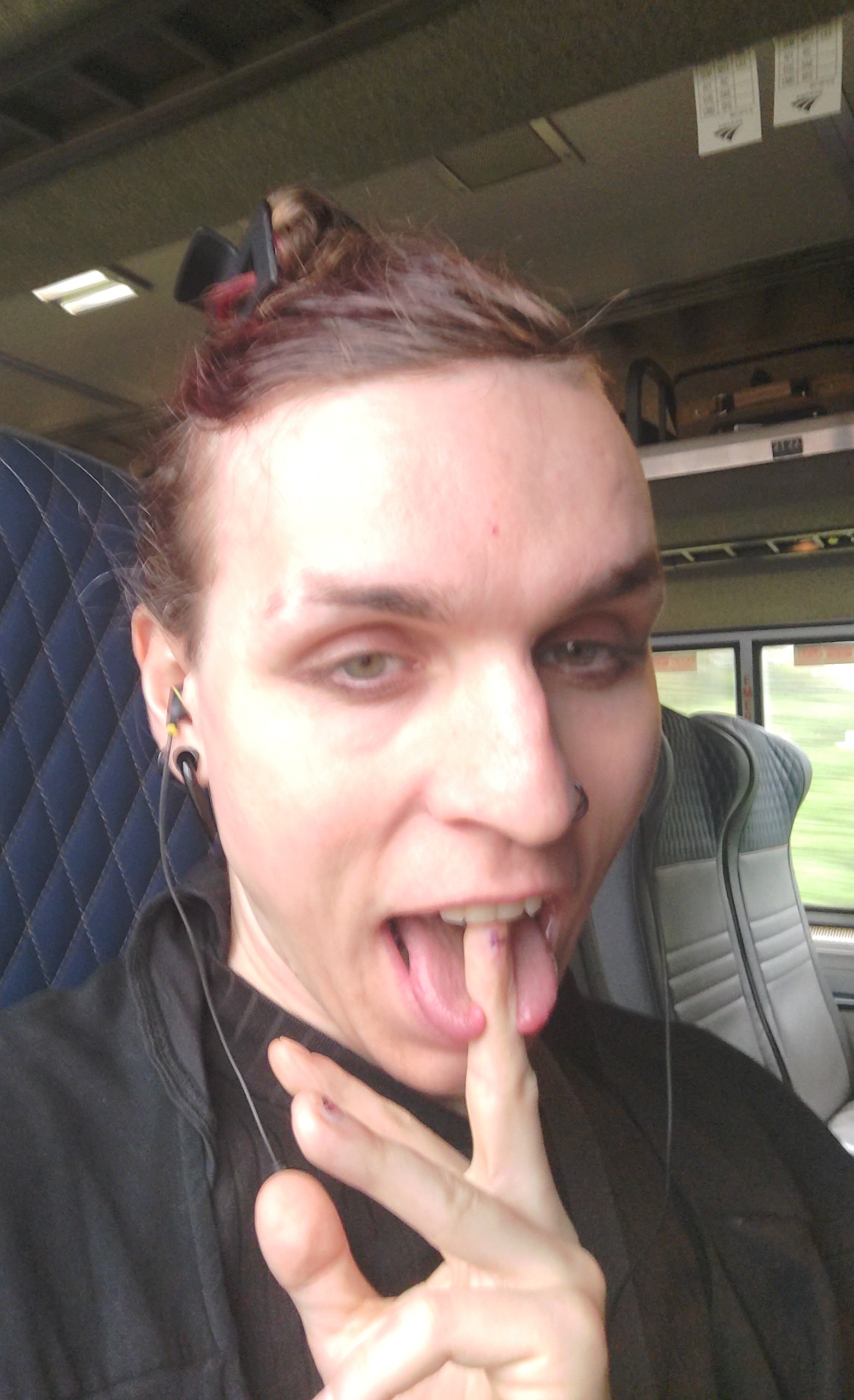 Vivi sticking their genital finger in their mouth between their tongues on a train
